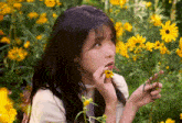 a woman smelling a yellow flower in a field of flowers