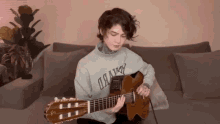 a person playing a guitar with a sweater that says " hawk " on it