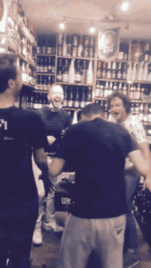 a man wearing a black shirt with the number 21 on it stands in front of a shelf full of bottles