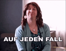 a woman wearing a blue sweater and a flower necklace says auf jeden fall