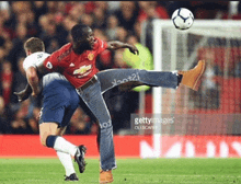 a man in jeans is kicking a soccer ball in a soccer game