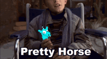 a boy in a wheelchair is holding a blue horse and the words " pretty horse " are above him