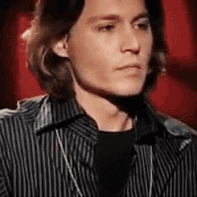 a close up of a man wearing a striped shirt and a black shirt with a necklace .