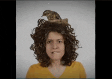 a woman with curly hair has a bird sitting on her head .