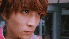 a close up of a person 's face with a pink shirt on .