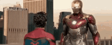 a man in a spiderman costume is standing next to a man in a iron man suit .