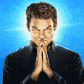 a man in a black shirt is praying with his hands folded