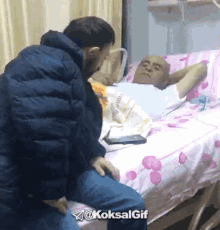 a man is kneeling down next to an elderly man in a hospital bed with the hashtag @koksalgif