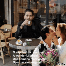 a man sitting at a table with a cup of coffee and a woman kissing him on the cheek