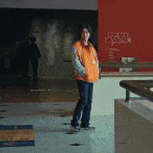 a woman in an orange jacket stands in front of a red wall that says ' texas '