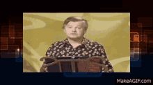 a man in a floral shirt is standing in front of a podium with makeagif.com written on the bottom