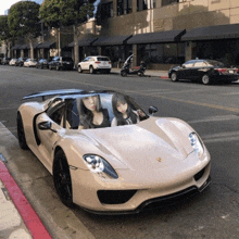 two women are sitting in a sports car on the street