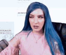 a woman with blue hair is wearing a pink top