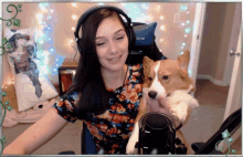 a woman wearing headphones holds a dog in front of a acer chair