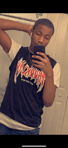 a young man taking a picture of himself in a mirror wearing a black shirt that says apocalypse
