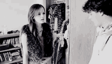 a man and a woman are standing next to each other in front of a closet full of clothes .