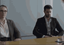 a man and a woman sit at a table in a conference room
