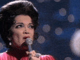 a woman singing into a microphone with a ring on her finger