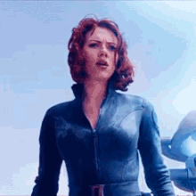 a woman in a blue suit with red hair is standing in front of a plane .