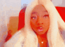 a blurry picture of a woman with blonde hair making a surprised face