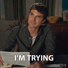 a man holding a piece of paper that says " i 'm trying " on it
