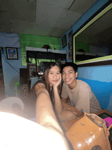 a man and a woman are posing for a picture in a room with a mirror