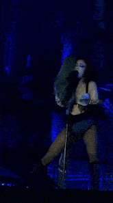 a woman is singing into a microphone while sitting on a stage
