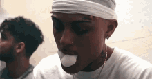 a man with a bandage on his head is smoking a cigarette while wearing a headband .