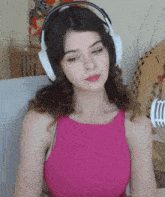a woman wearing headphones and a pink top is sitting in front of a microphone