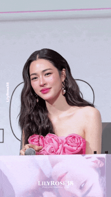 a woman in a pink dress is holding a pink rose and a sign that says lily rose 38
