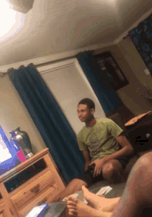 a man in a green shirt sits on a couch with his feet up