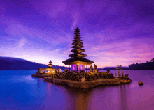 a small island in the middle of a lake with a purple sky