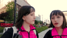 two women standing next to each other with one wearing a pink jacket that says ' abercrombie & fitch ' on it