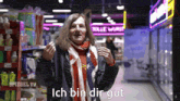 a man wearing an american flag scarf says ich bin dir gut in a store