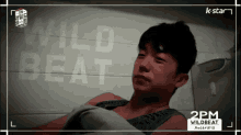 a young man is laying down in front of a sign that says wildbeat