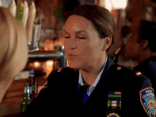 a woman in a police uniform is blowing a kiss at a bar