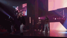 a group of people singing on a stage with a large screen in the background