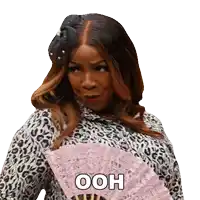 a woman in a leopard print shirt is holding a pink fan with the word ooh on it