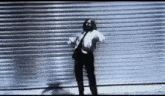 a man with dreadlocks is dancing in front of a metal garage door .
