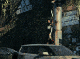 a woman is standing on top of a car in front of a building that says adidas