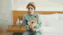 a woman is sitting on a bed holding a mickey mouse stuffed animal .