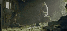 a man is playing a guitar in a dark room while a woman sits on the floor next to a chainsaw .