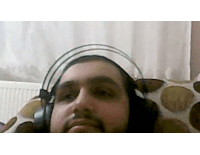 a man with a beard is wearing headphones while laying on a bed .