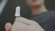 a close up of a person holding a stick of lip balm that says ' lip balm ' on it