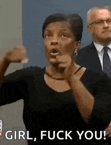 a woman in a black shirt is pointing at a man in a suit and tie .