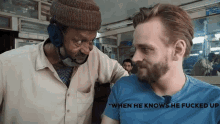 a man in a blue shirt is talking to another man in a tan shirt