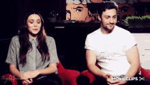 a man and a woman are sitting next to each other and the man is wearing a white shirt that says movieclips