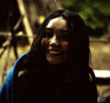 a woman wrapped in a blue blanket is smiling in the dark .