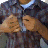a man wearing a plaid shirt has his hands on his chest