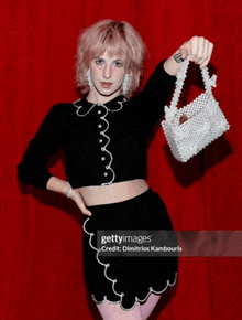 a woman with pink hair is holding a white bag